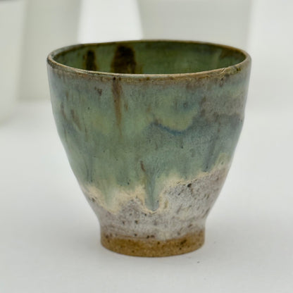 Green ceramic pot with a textured surface on a white background