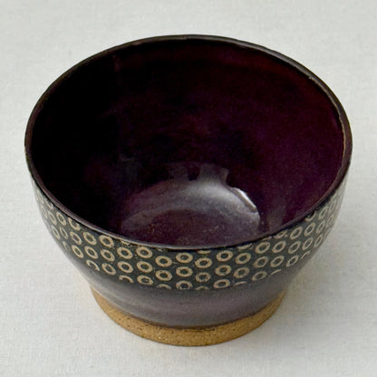 Purple ceramic bowl with circular pattern on a white background