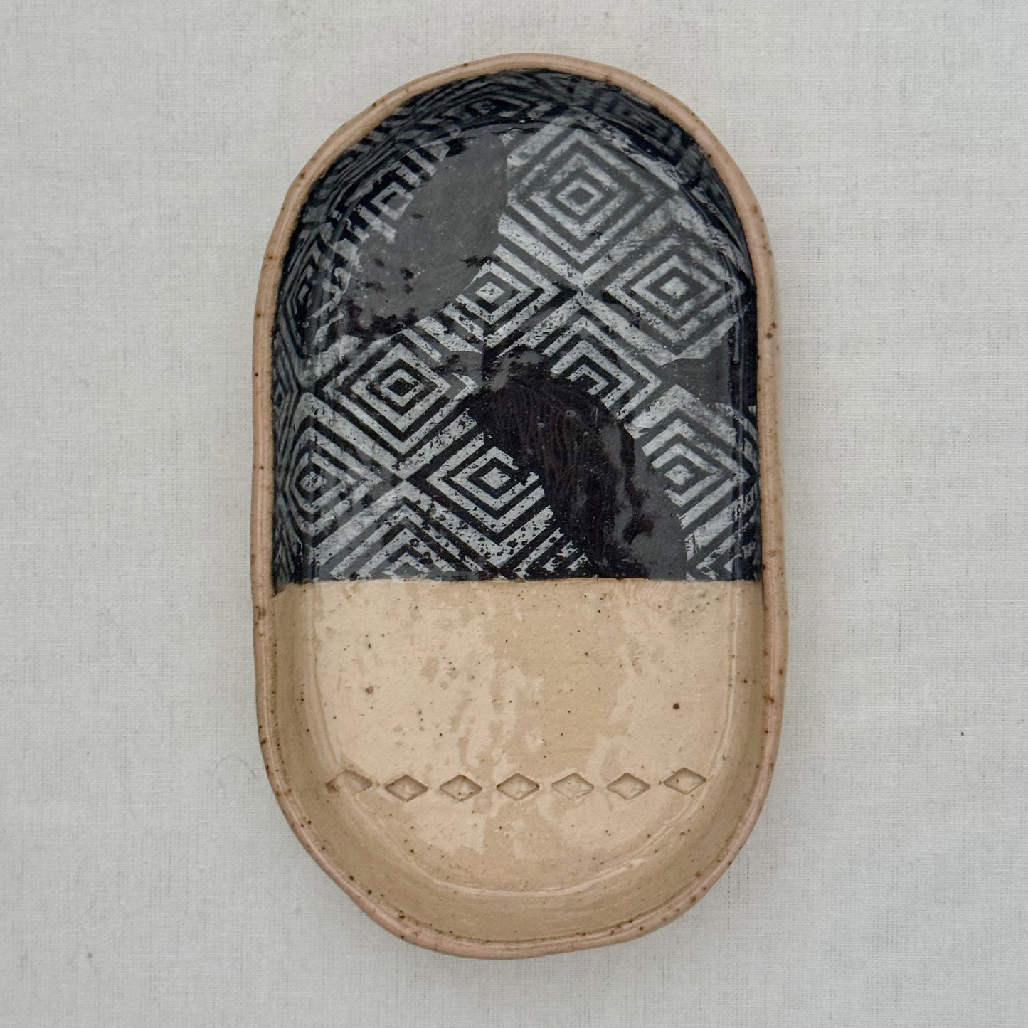 Oval ceramic dish with black and white geometric pattern on a beige base