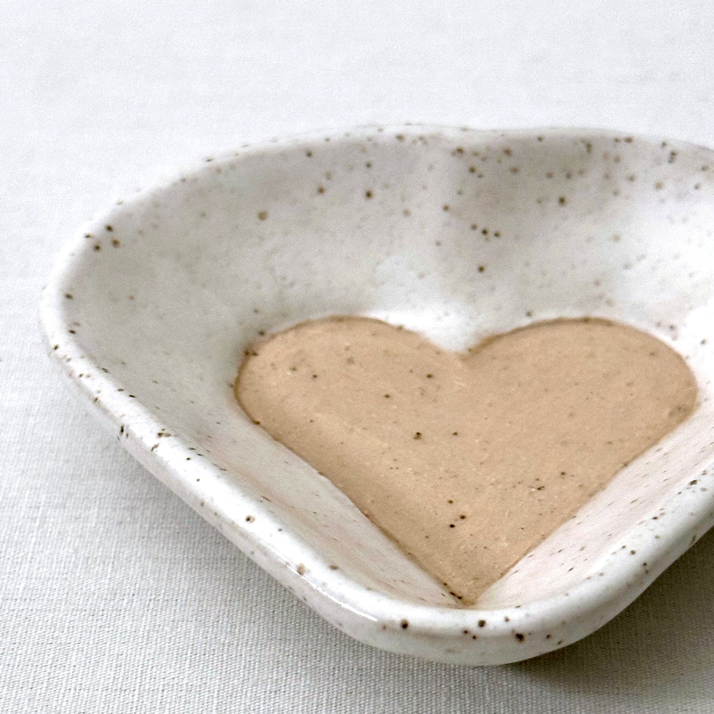 Heart-shaped ceramic dish with a light pink heart inside on a light background