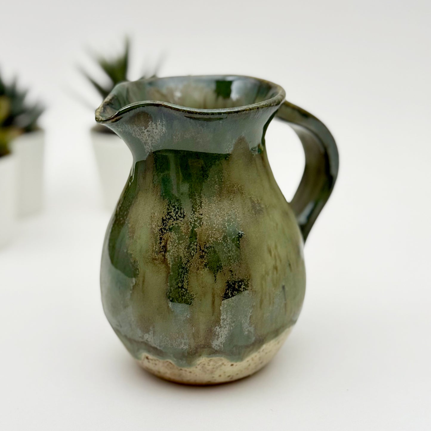 Green ceramic pitcher on a white background