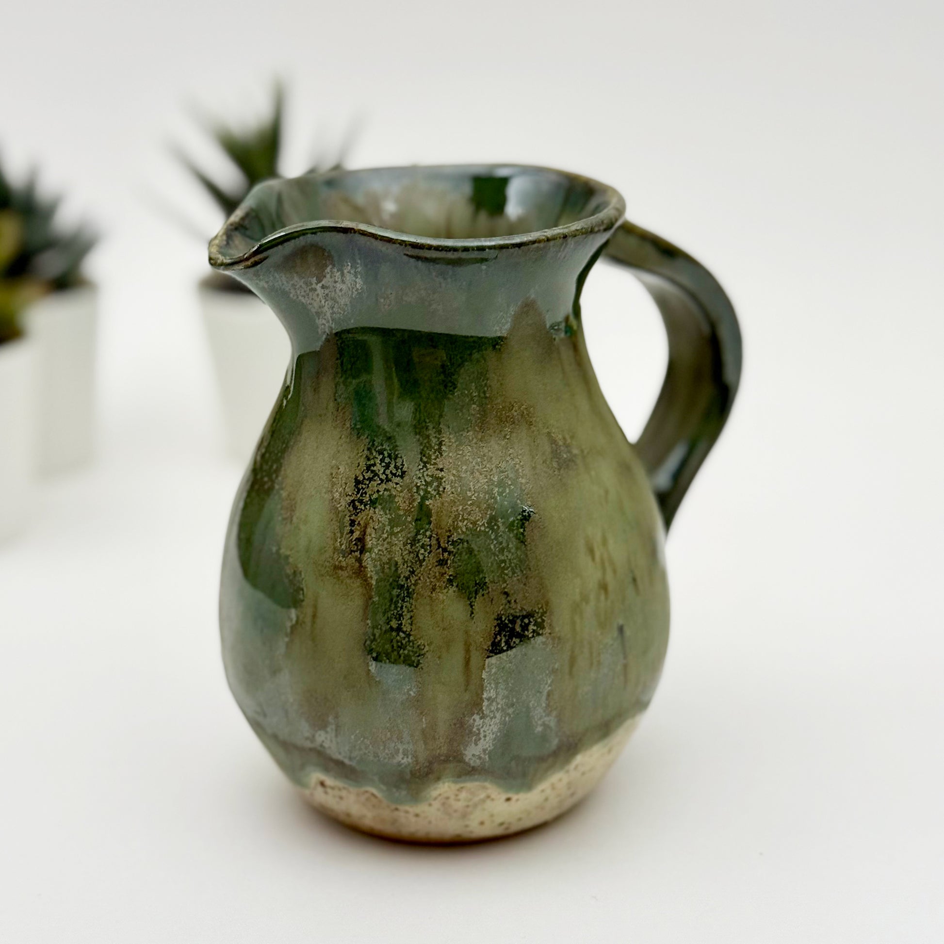 Green ceramic pitcher on a white background