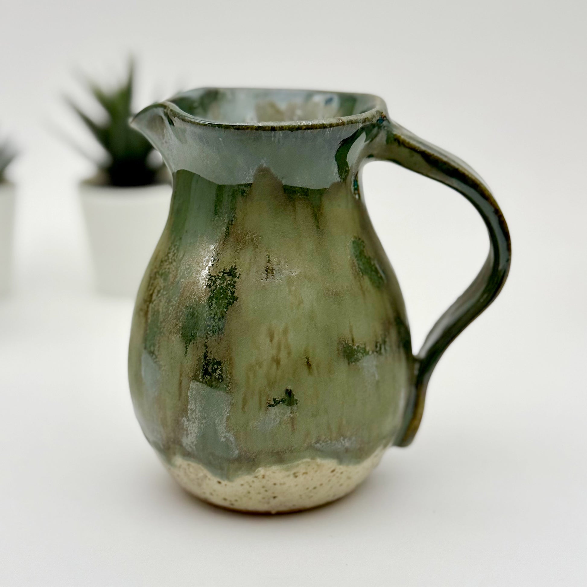 Green ceramic pitcher on a white background