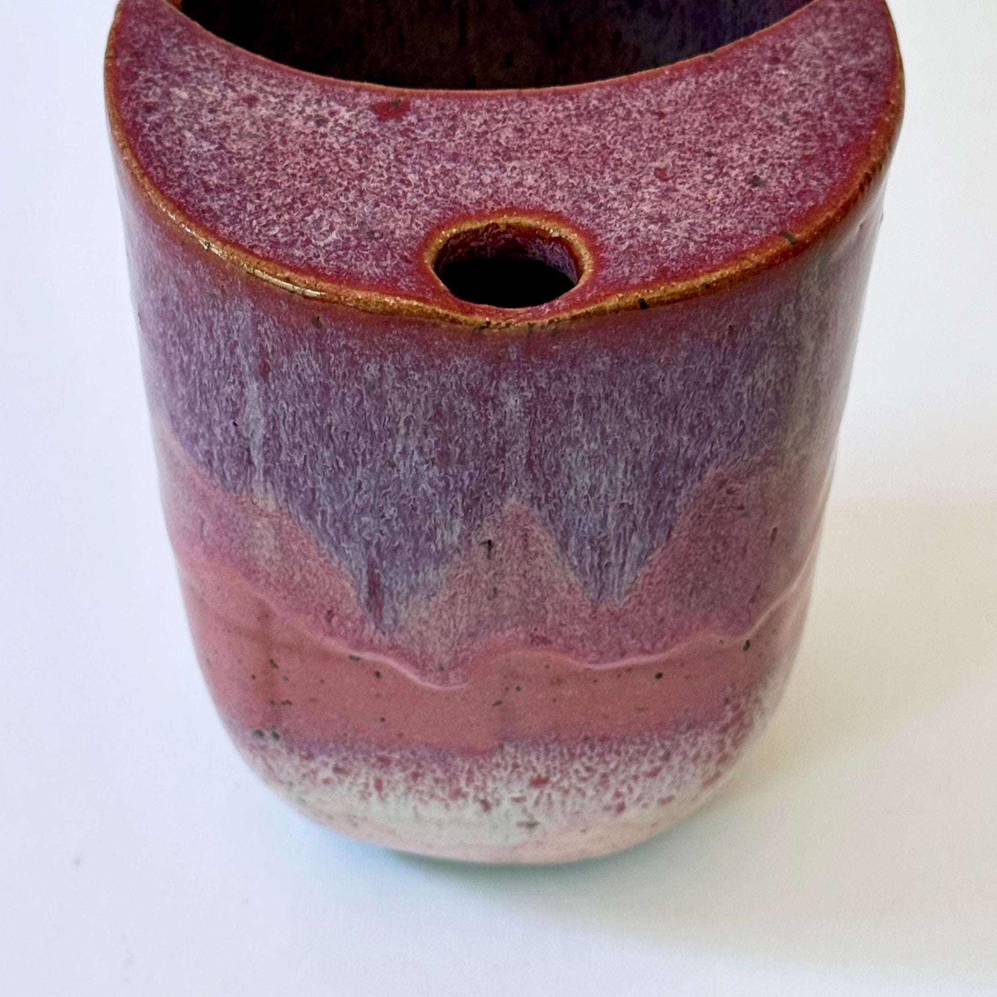 Handmade stoneware to-go mug featuring layered tonal pink glaze from deep berry to soft blush over speckled clay.