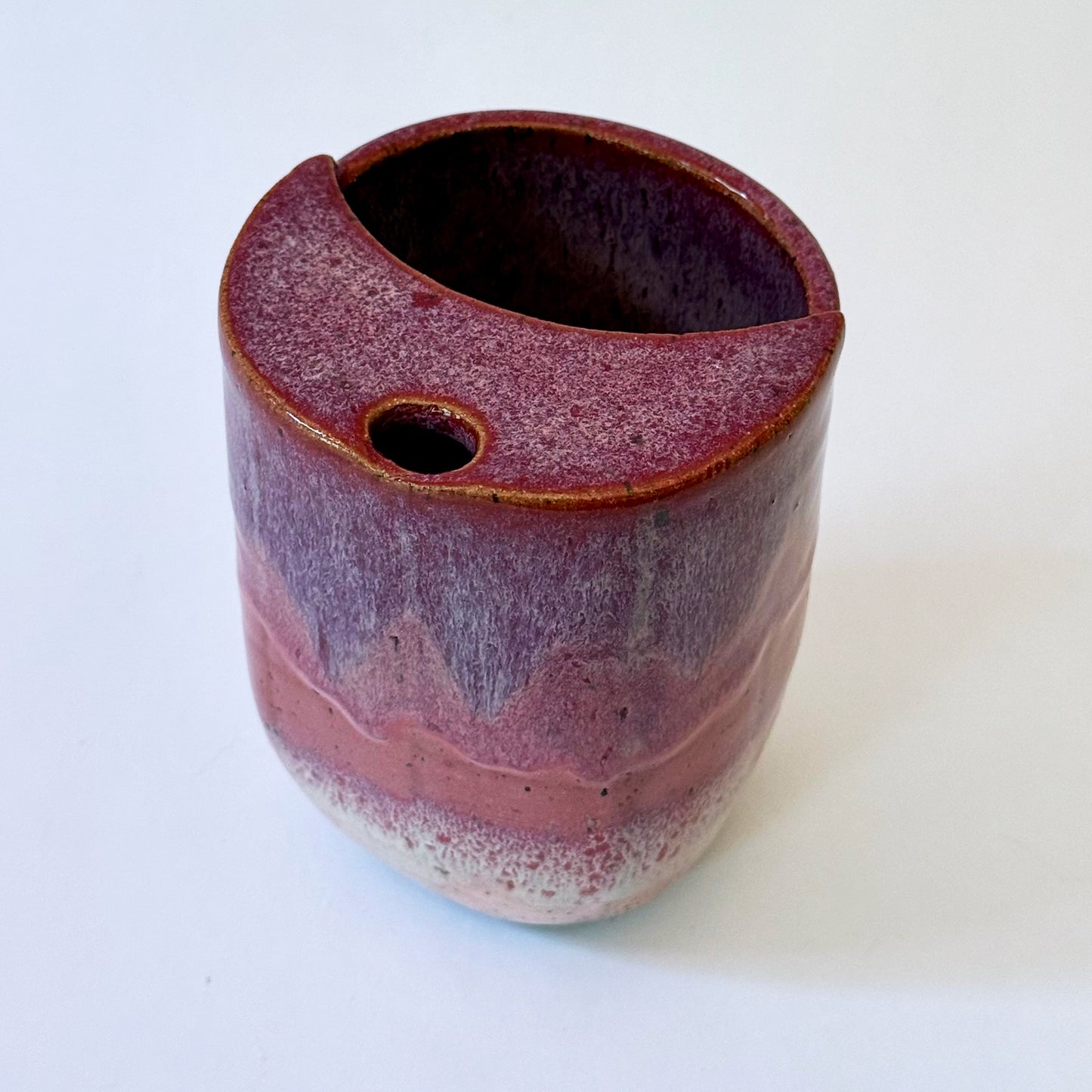 Handmade stoneware to-go mug featuring layered tonal pink glaze from deep berry to soft blush over speckled clay.