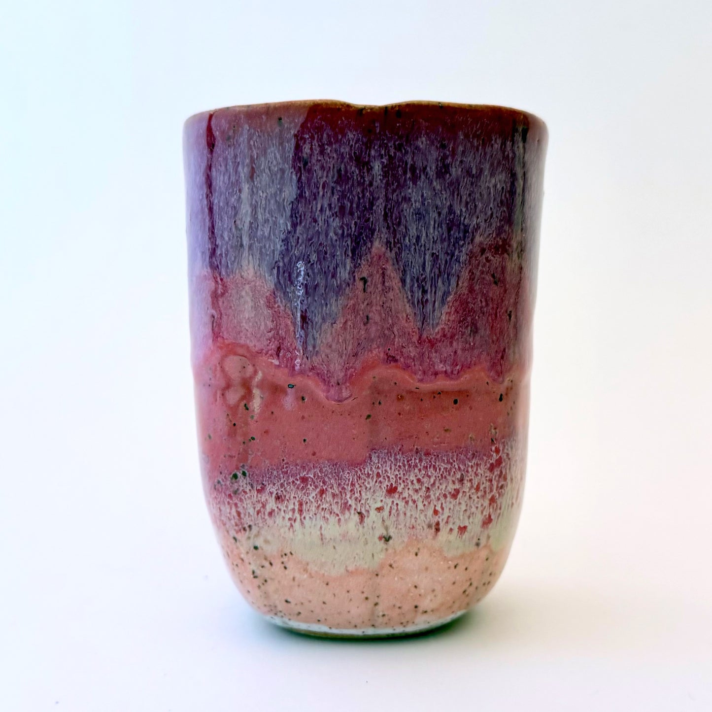 Handmade stoneware to-go mug featuring layered tonal pink glaze from deep berry to soft blush over speckled clay.