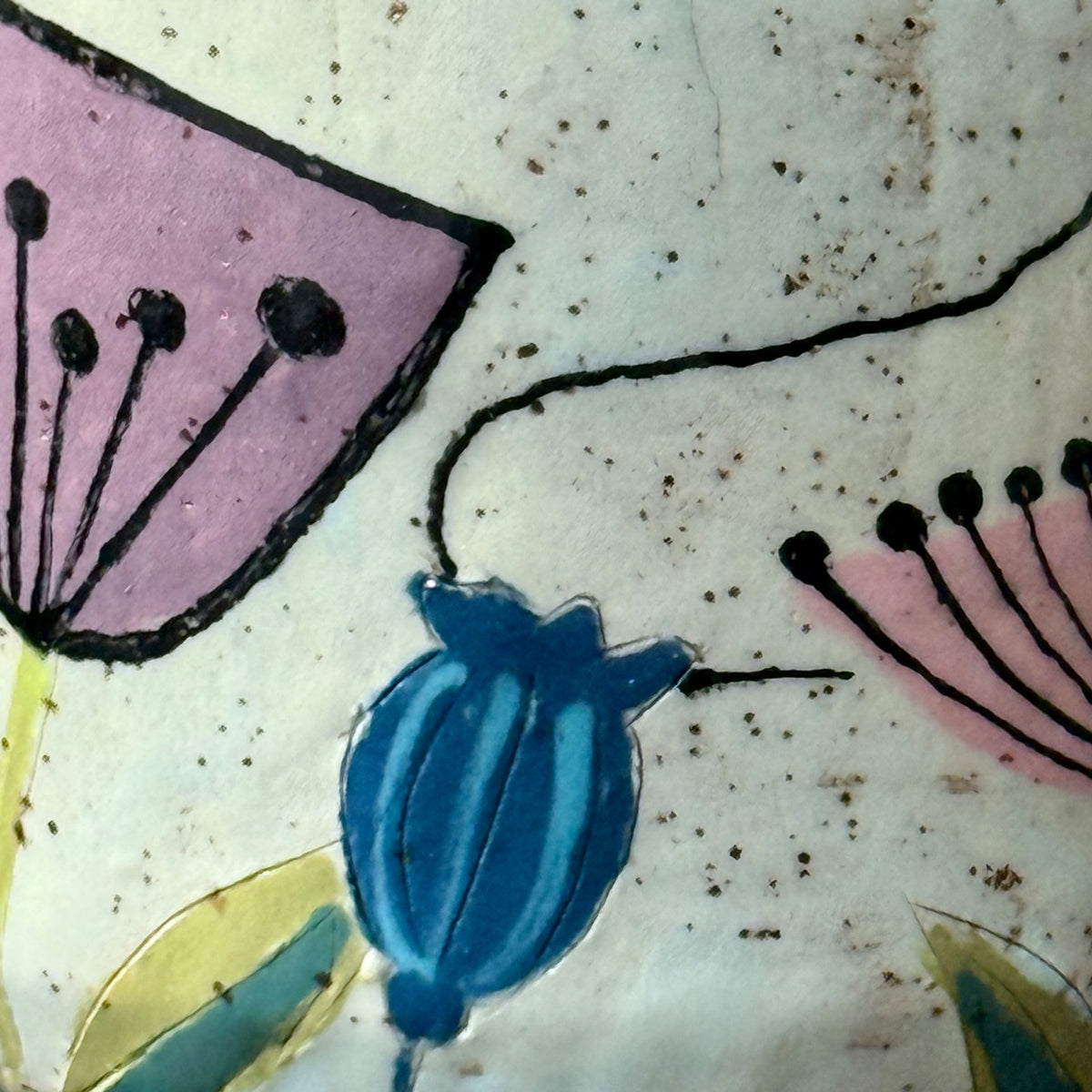 Close up of handcrafted mid-century modern ceramic mug with pink and purple retro flower illustrations, blue seed pods, and atomic starbursts on a speckled cream background.