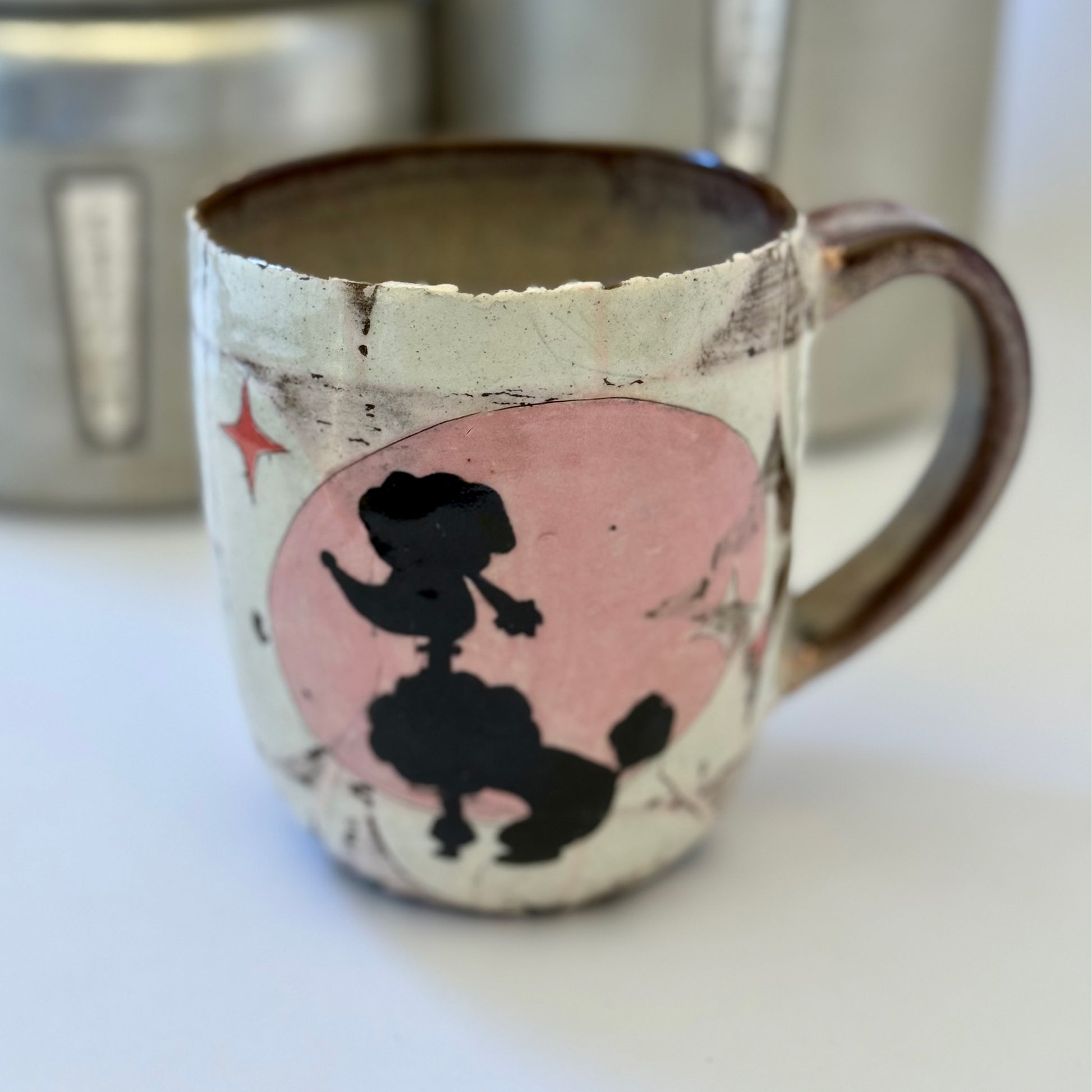 Pink-and-white ceramic mug featuring a black retro poodle silhouette against a pink circle.