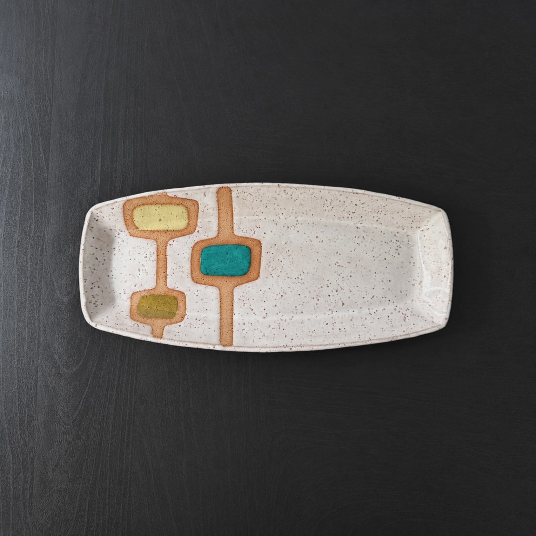 Three handmade rectangular ceramic trays with softly rounded corners, finished in a glossy white glaze with exposed speckled clay forming mid-century geometric designs. Accents of turquoise blue, mustard yellow, and olive green add pops of color across the three different patterns.