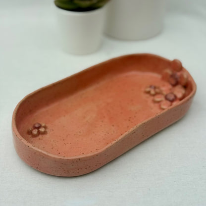 Pink ceramic dish with floral design on a white surface