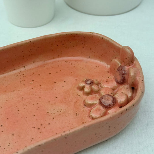 Pink ceramic dish with floral design on a white surface