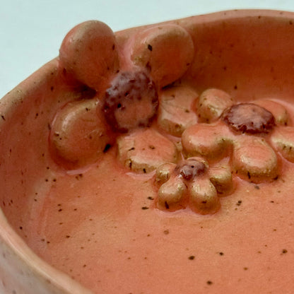 Pink ceramic dish with floral design on a white surface