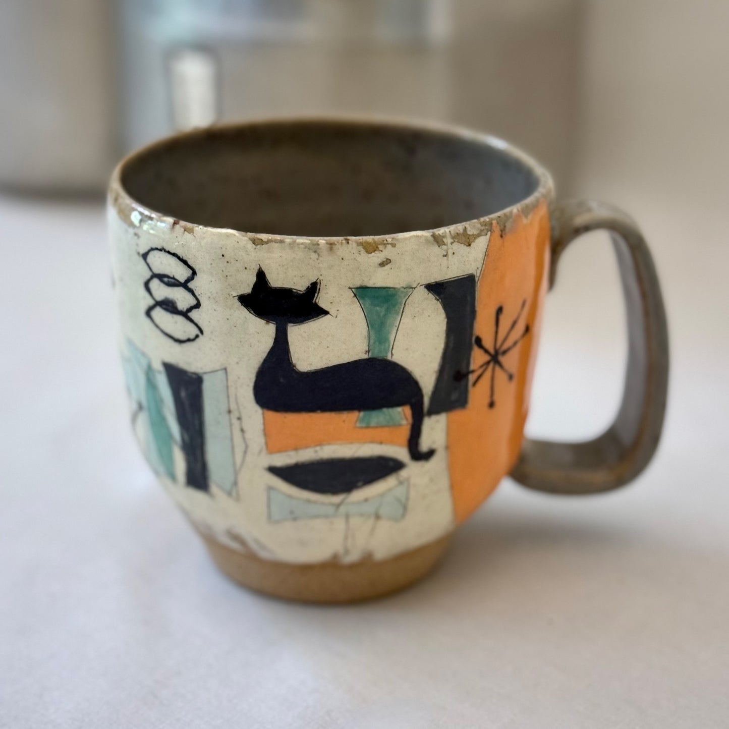 Ceramic mug with mid century design featuring a cat on a white surface