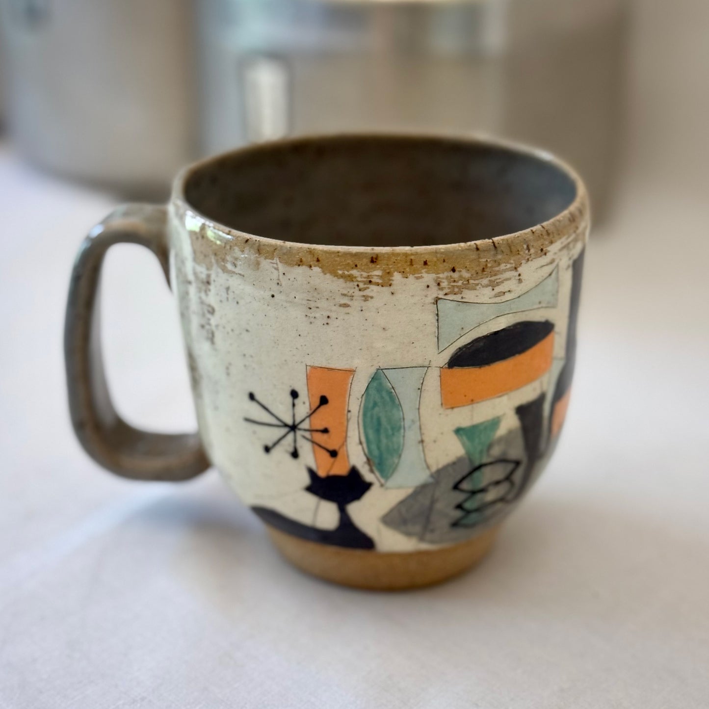 Ceramic mug with mid century design featuring a cat on a white surface