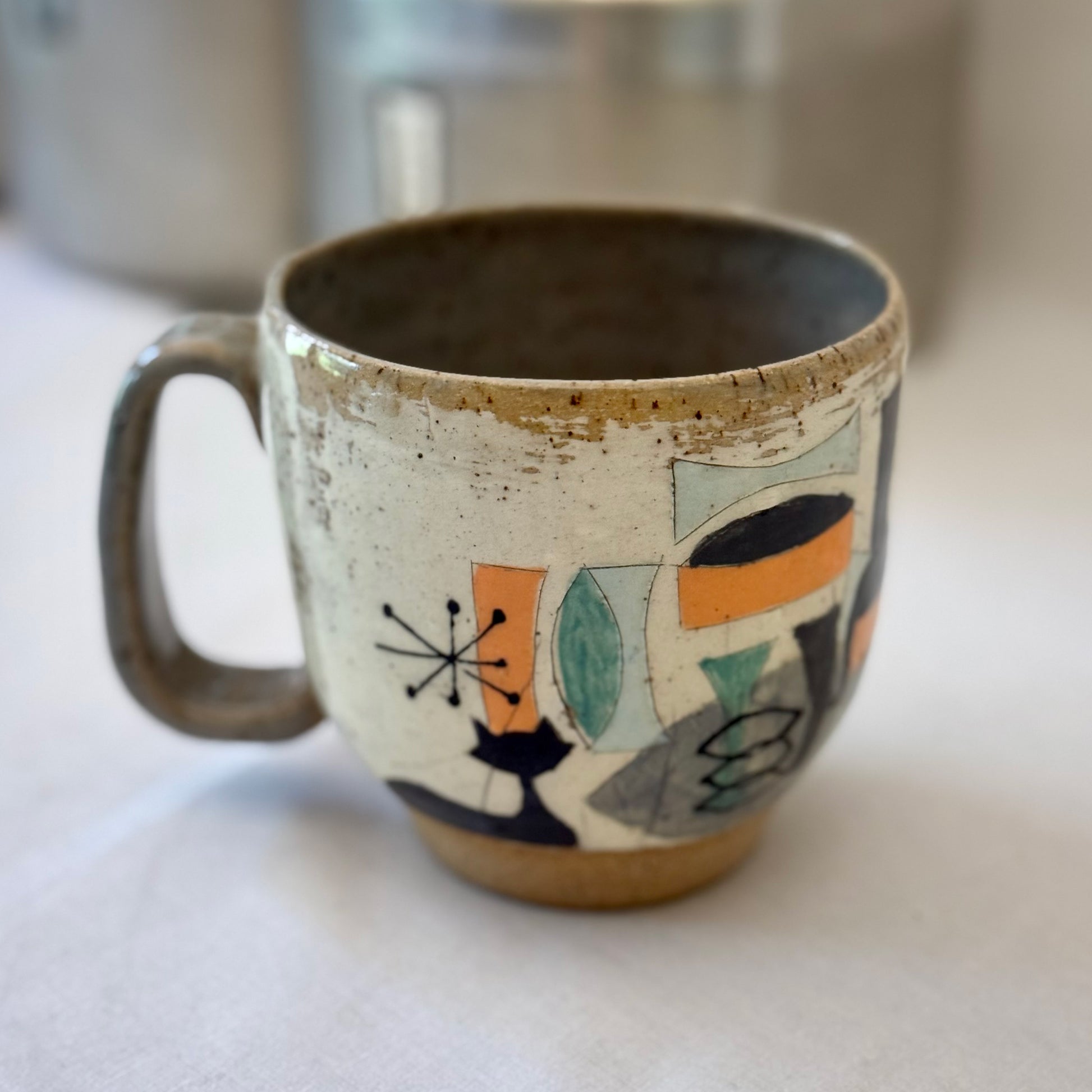 Ceramic mug with mid century design featuring a cat on a white surface