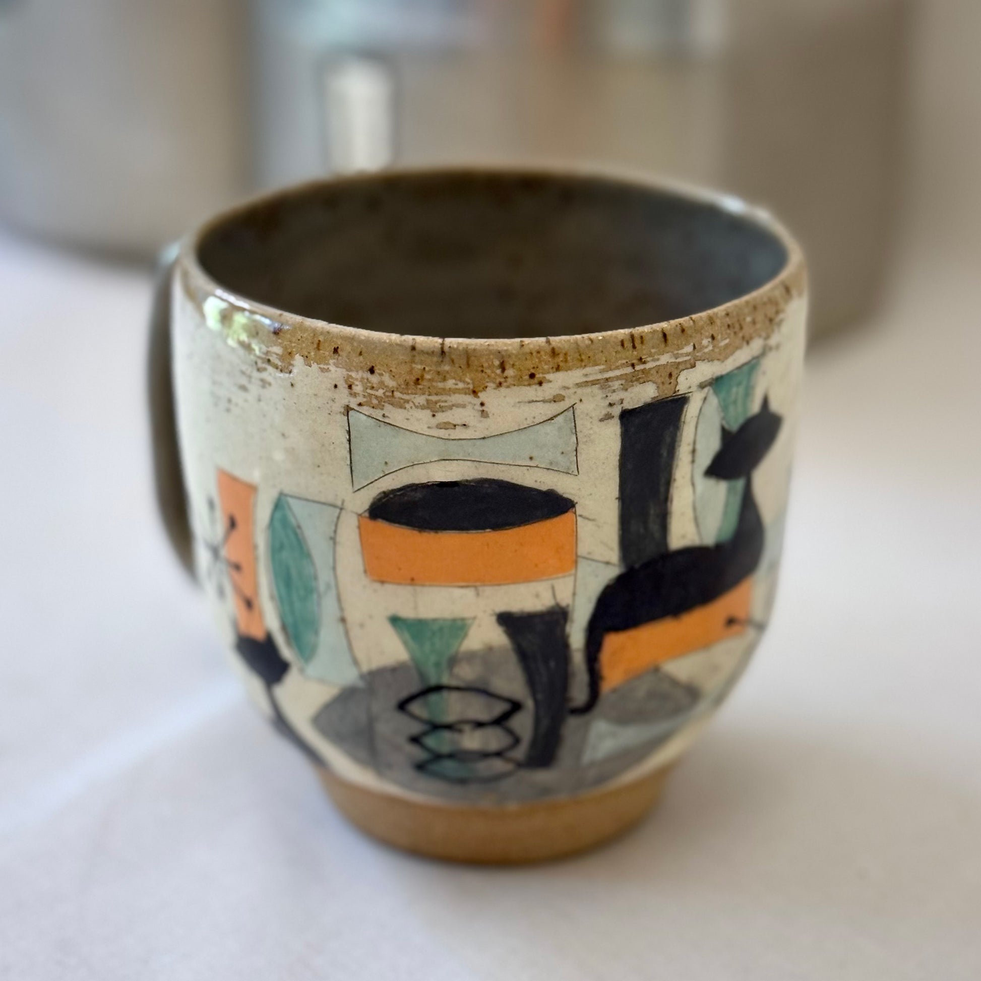 Ceramic mug with mid century design featuring a cat on a white surface