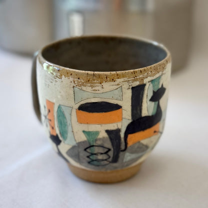 Ceramic mug with mid century design featuring a cat on a white surface