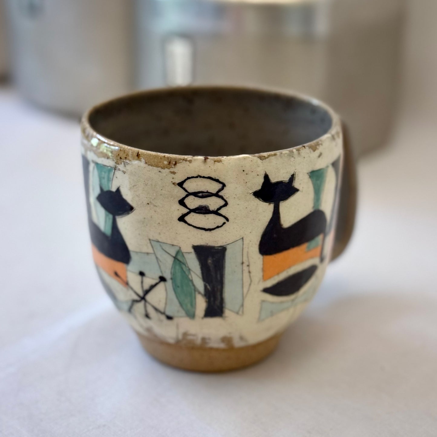 Ceramic mug with mid century design featuring a cat on a white surface