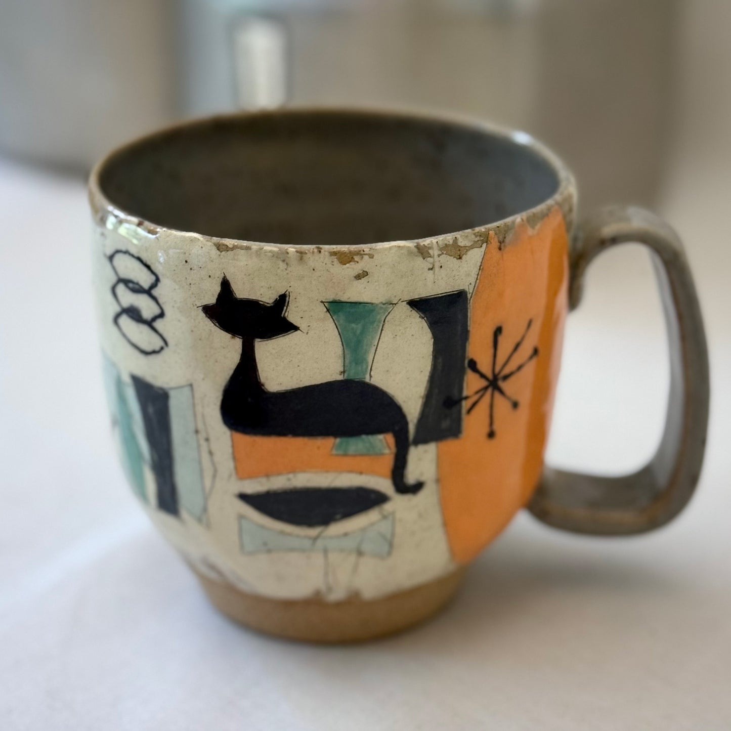 Ceramic mug with mid century design featuring a cat on a white surface