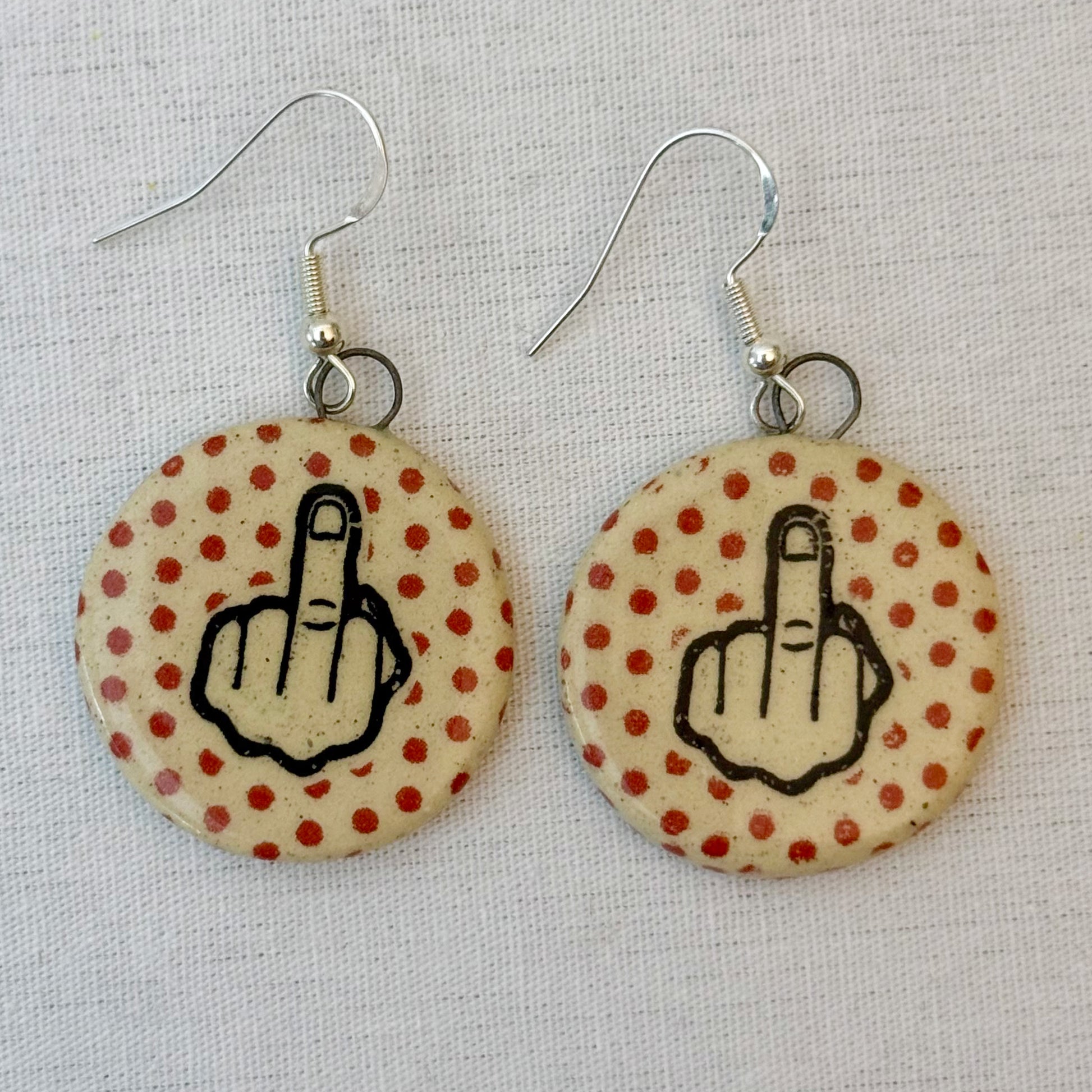 Earrings with middle finger symbol on polka dot background