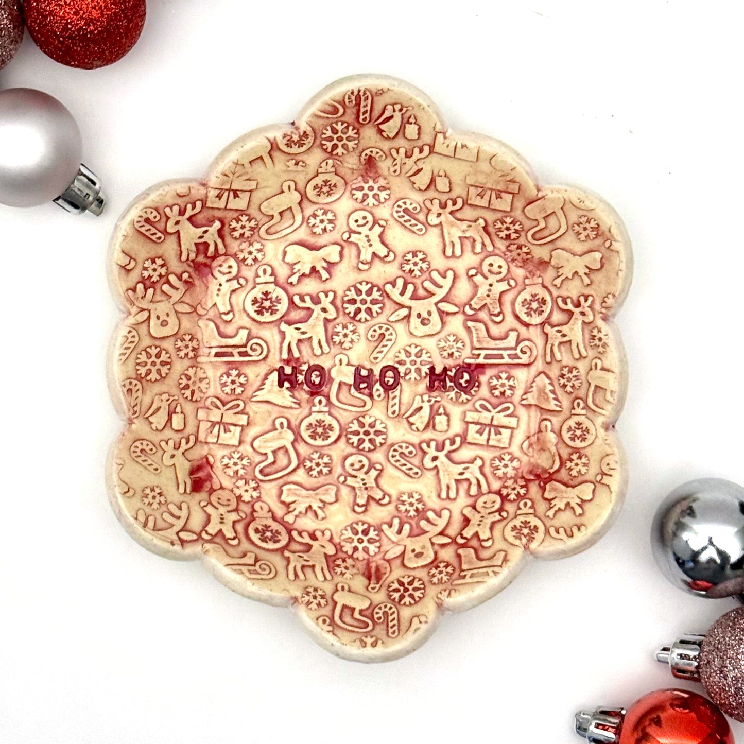 Decorative cookie with Christmas-themed designs and 'HO HO HO' text, surrounded by festive ornaments on a white background.
