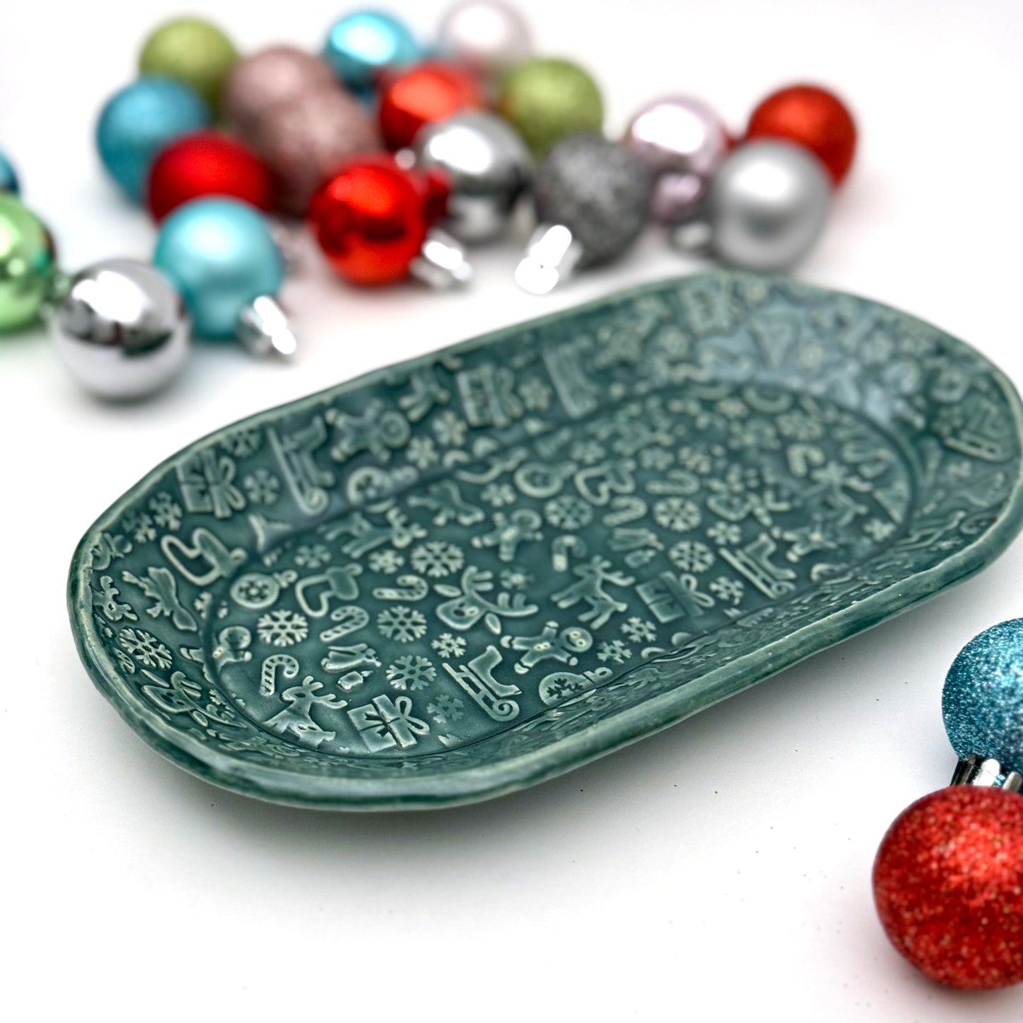 Decorative green plate with holiday patterns on a white background with colorful ornaments.