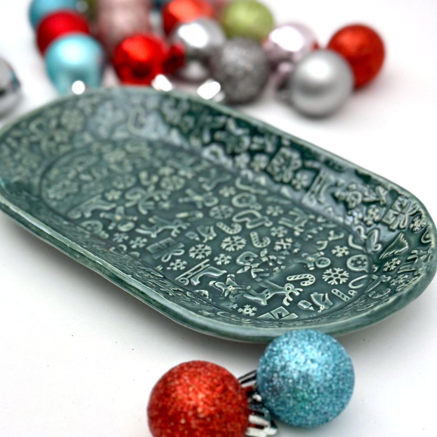 Decorative green plate with holiday patterns on a white background with colorful ornaments.