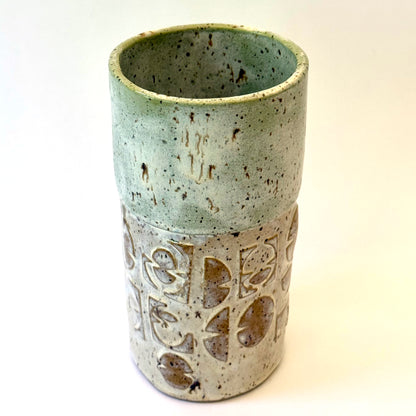 Handmade stoneware vase with layered green glaze over textured surface and speckled clay base.