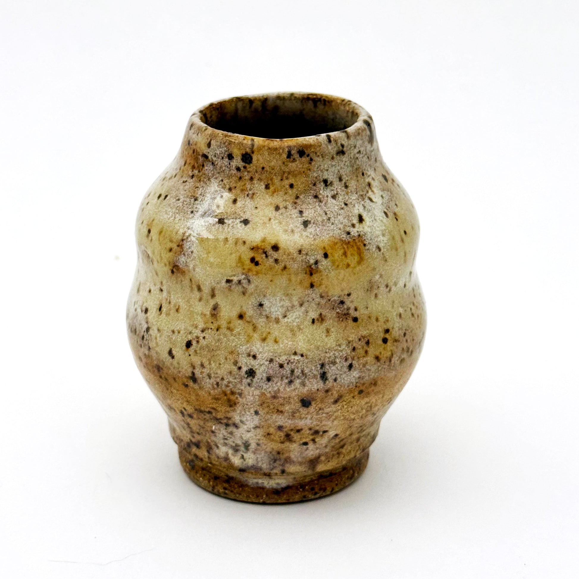 Small handmade stoneware bud vase with rounded shape and narrow opening, finished in a warm speckled glaze in cream, tan, and brown.