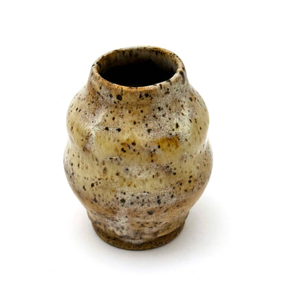 Small handmade stoneware bud vase with rounded shape and narrow opening, finished in a warm speckled glaze in cream, tan, and brown.