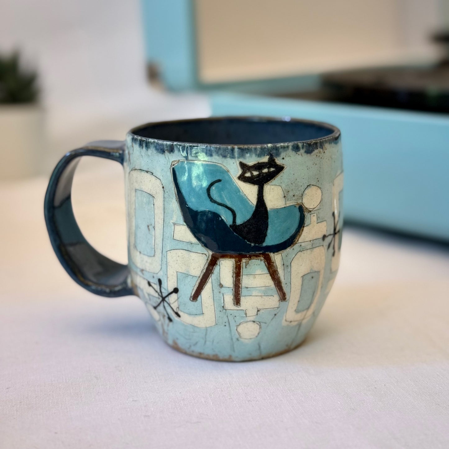 Handmade mug with black cat sitting in mid-century chair and atomic shapes