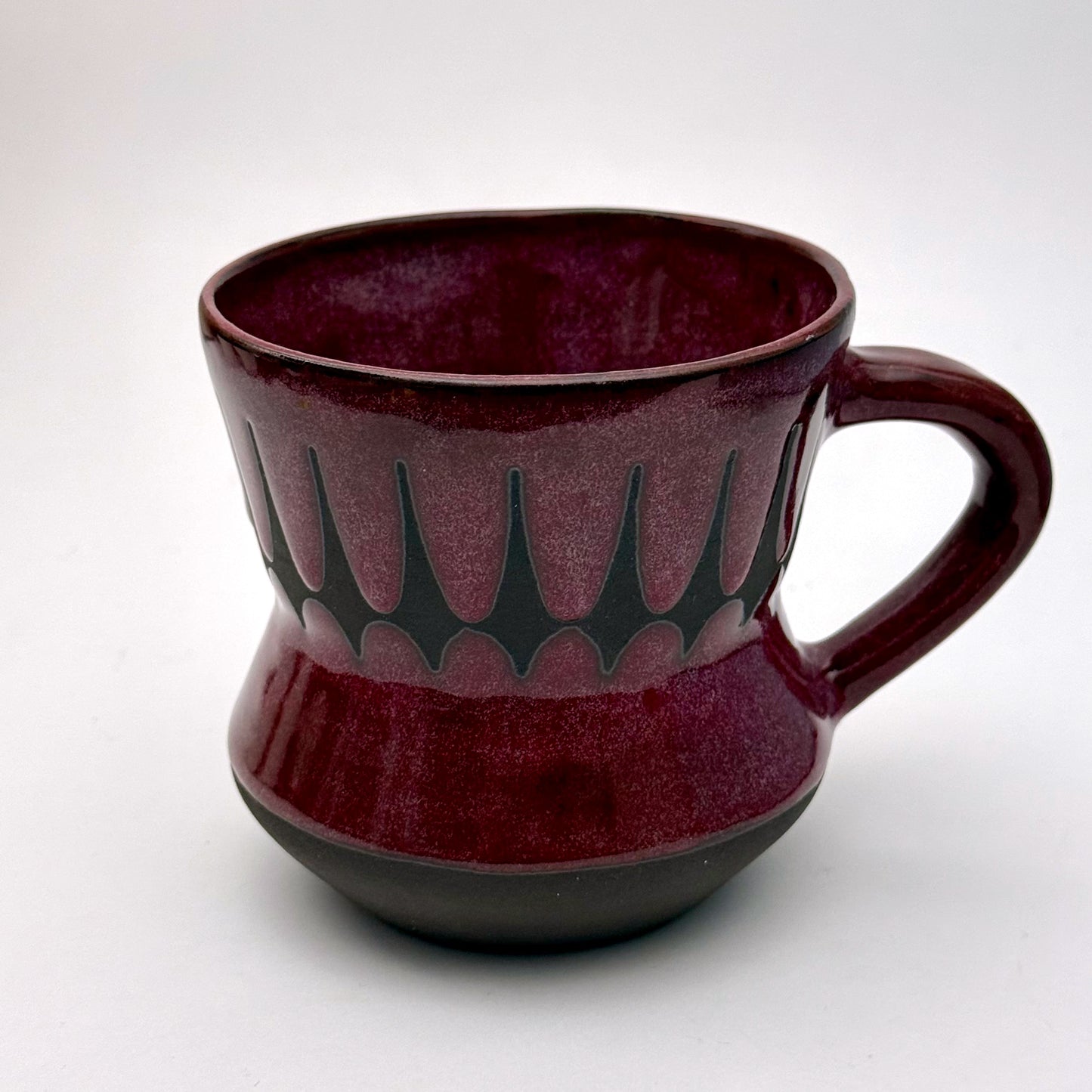 Handmade ceramic mug finished in a rich red glaze with a mid-century–inspired patterned band.