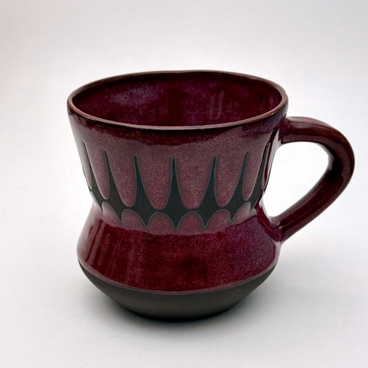 Handmade ceramic mug finished in a rich red glaze with a mid-century–inspired patterned band.