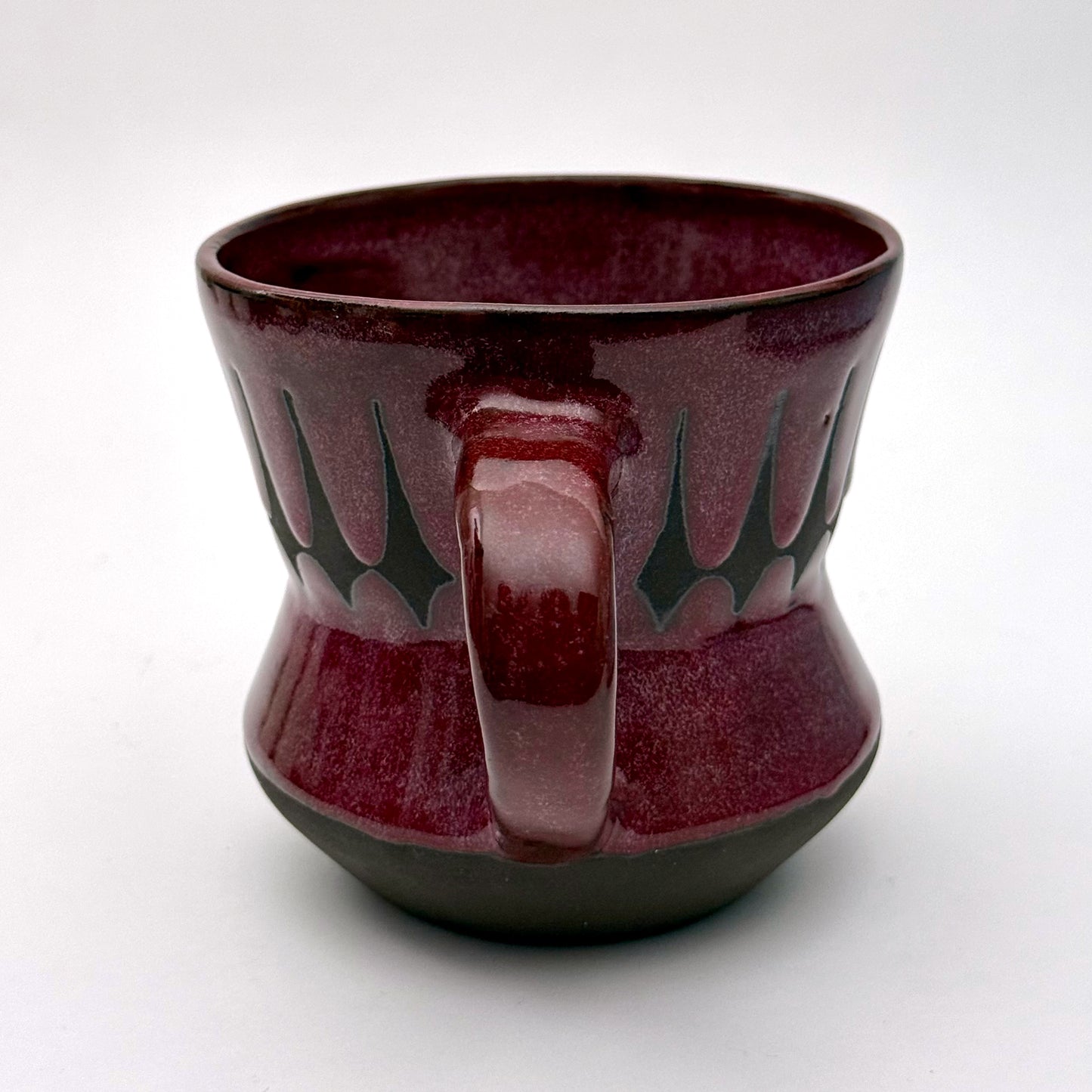 Handmade ceramic mug finished in a rich red glaze with a mid-century–inspired patterned band.