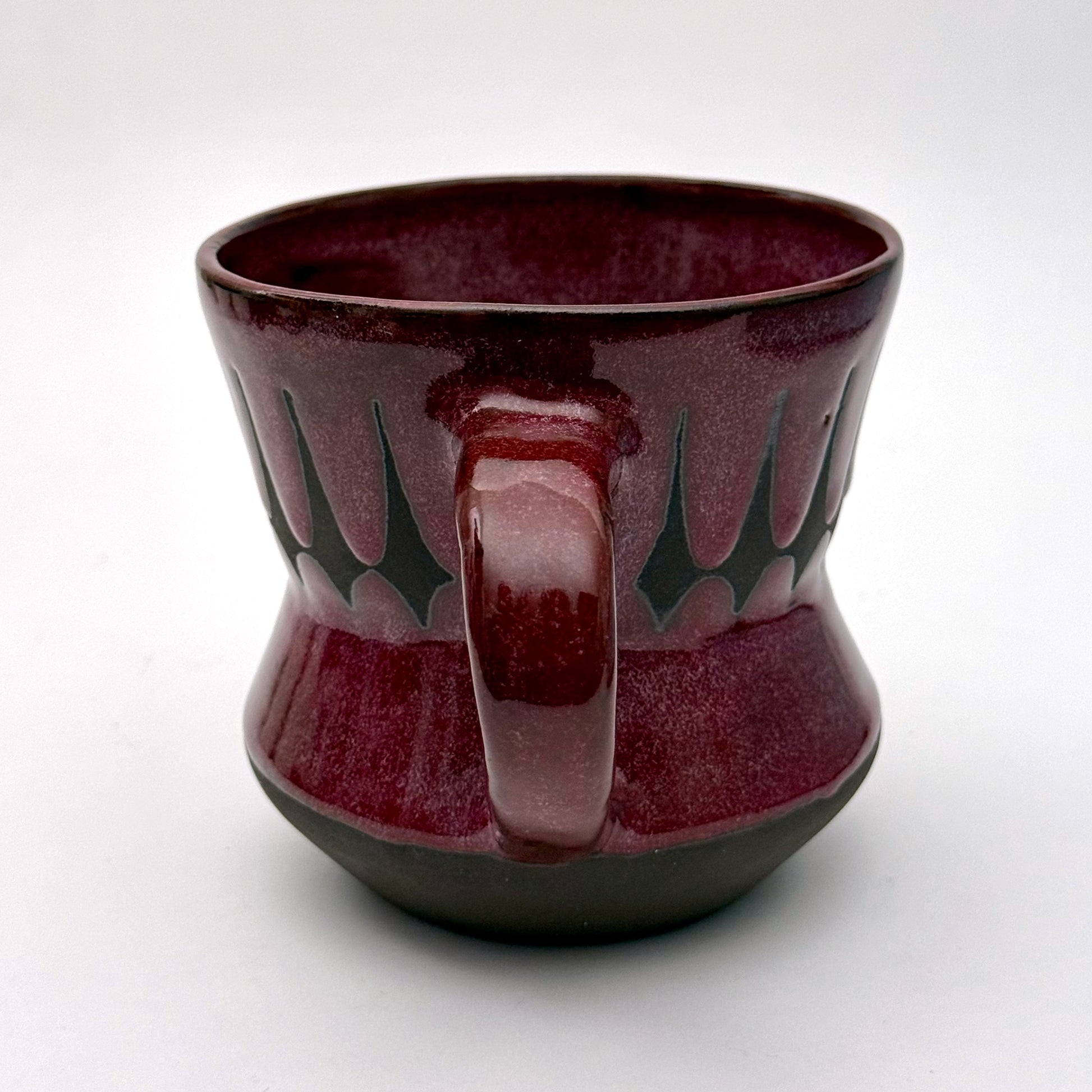 Handmade ceramic mug finished in a rich red glaze with a mid-century–inspired patterned band.