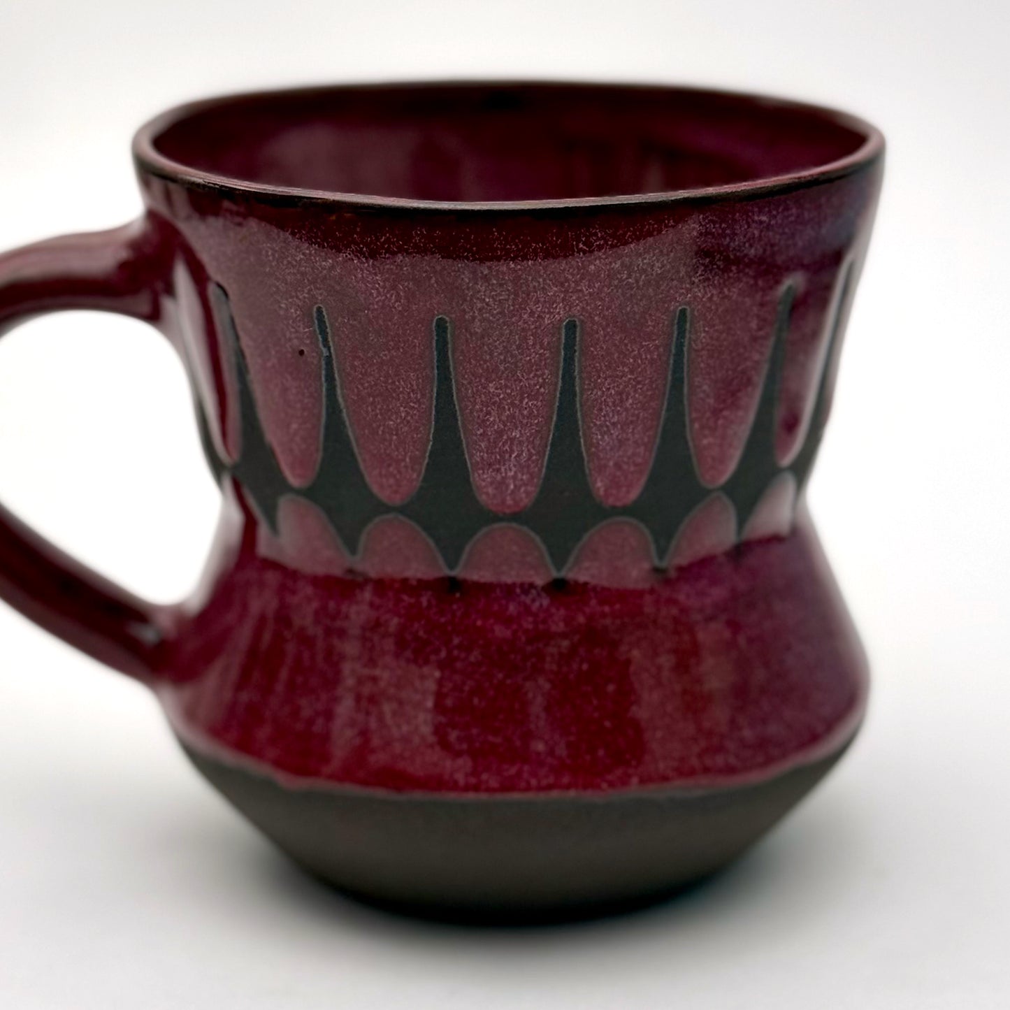 Handmade ceramic mug finished in a rich red glaze with a mid-century–inspired patterned band.