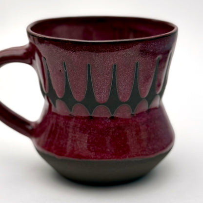 Handmade ceramic mug finished in a rich red glaze with a mid-century–inspired patterned band.