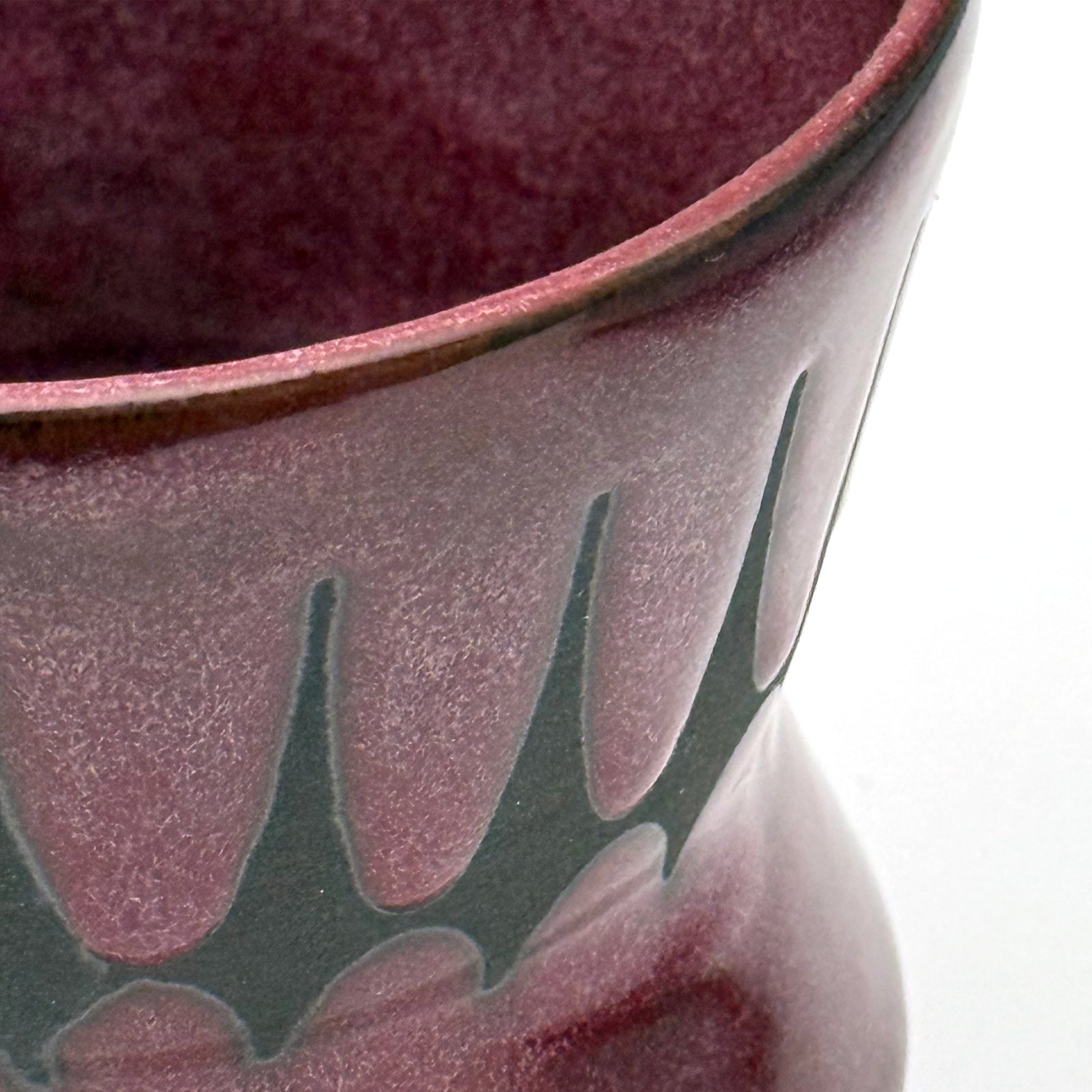 Close-up of handmade ceramic mug finished in a rich red glaze with a mid-century–inspired patterned band.