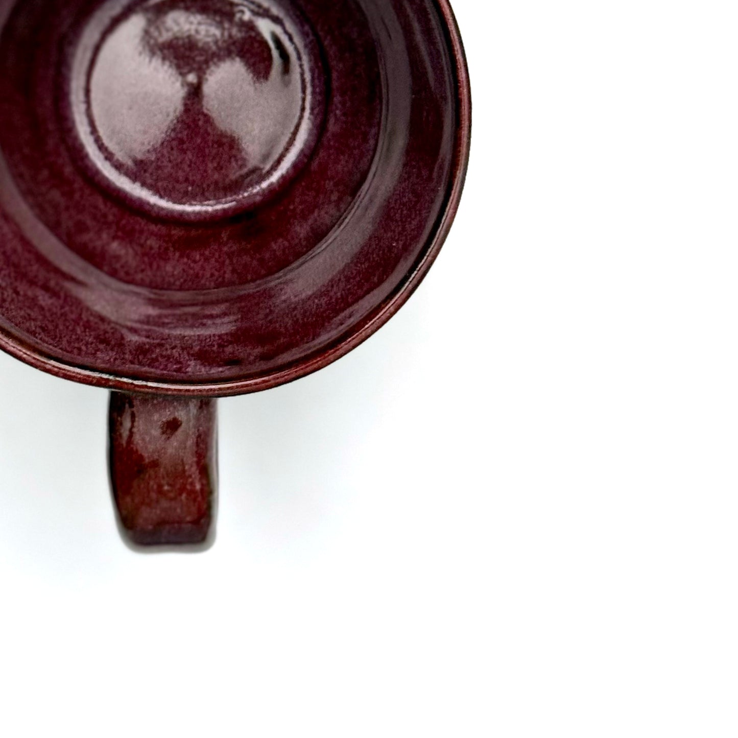 Top view of a handmade ceramic mug finished in a rich red glaze with a mid-century–inspired patterned band.