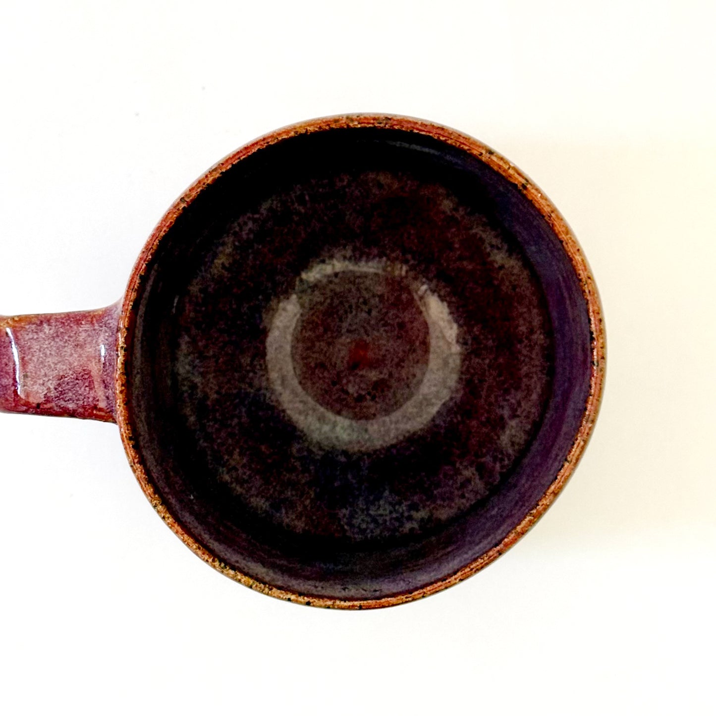 Interior view of a sturdy, red-glazed mug featuring a repeating geometric tulip pattern in raw, speckled tan stoneware. The design uses sharp lines and a bold, angular handle to create a retro, architectural silhouette.