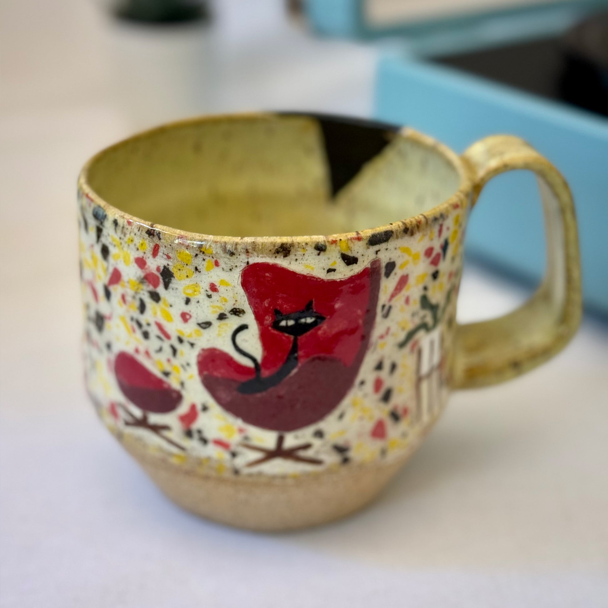 Handmade mug with black cat in red chair and terrazzo pattern