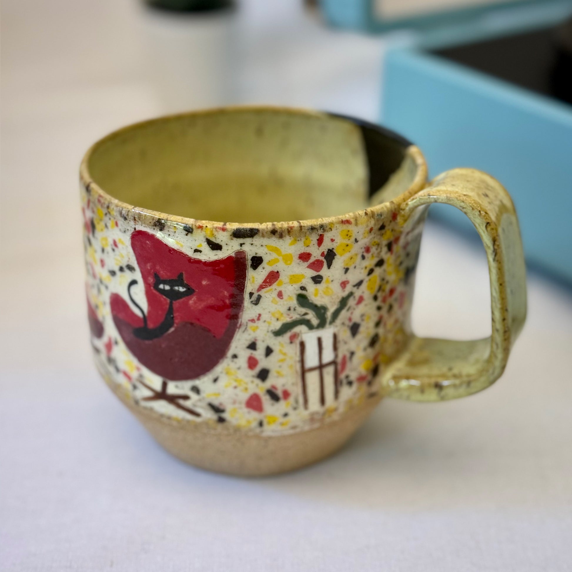 Handmade mug with black cat in red chair and terrazzo pattern