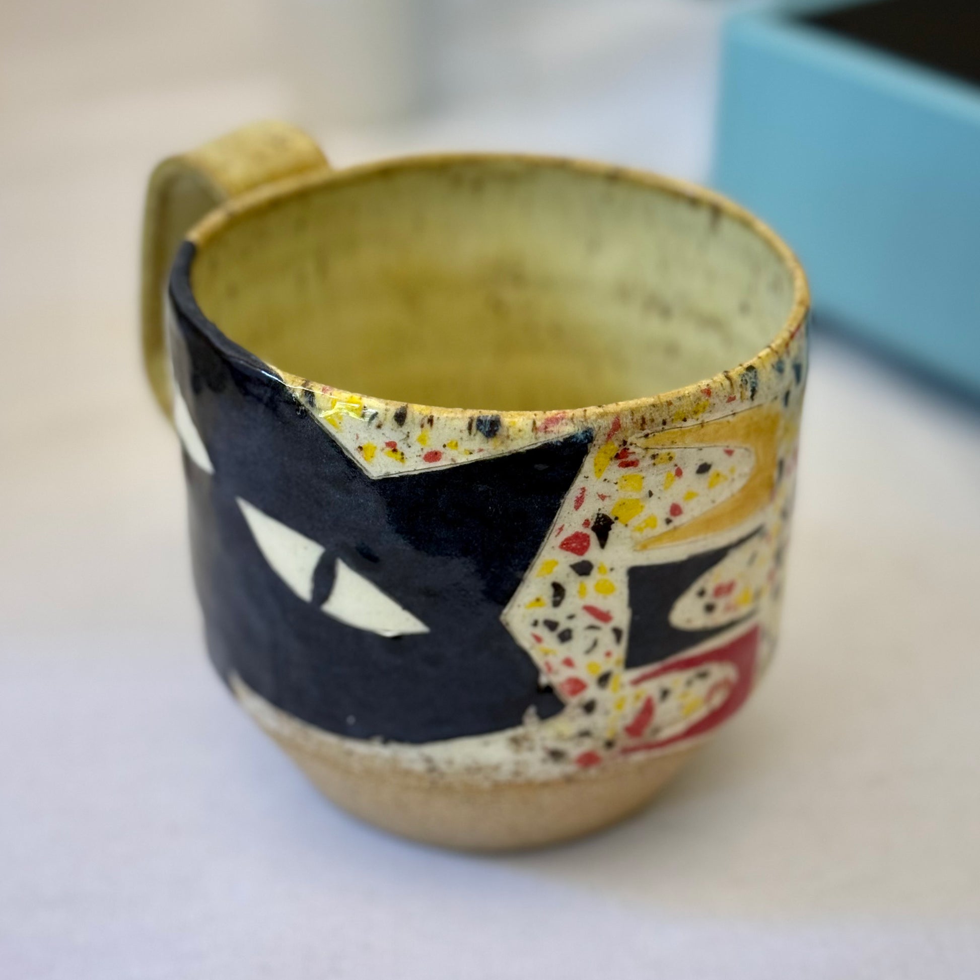 Handmade mug with black cat in red chair and terrazzo pattern