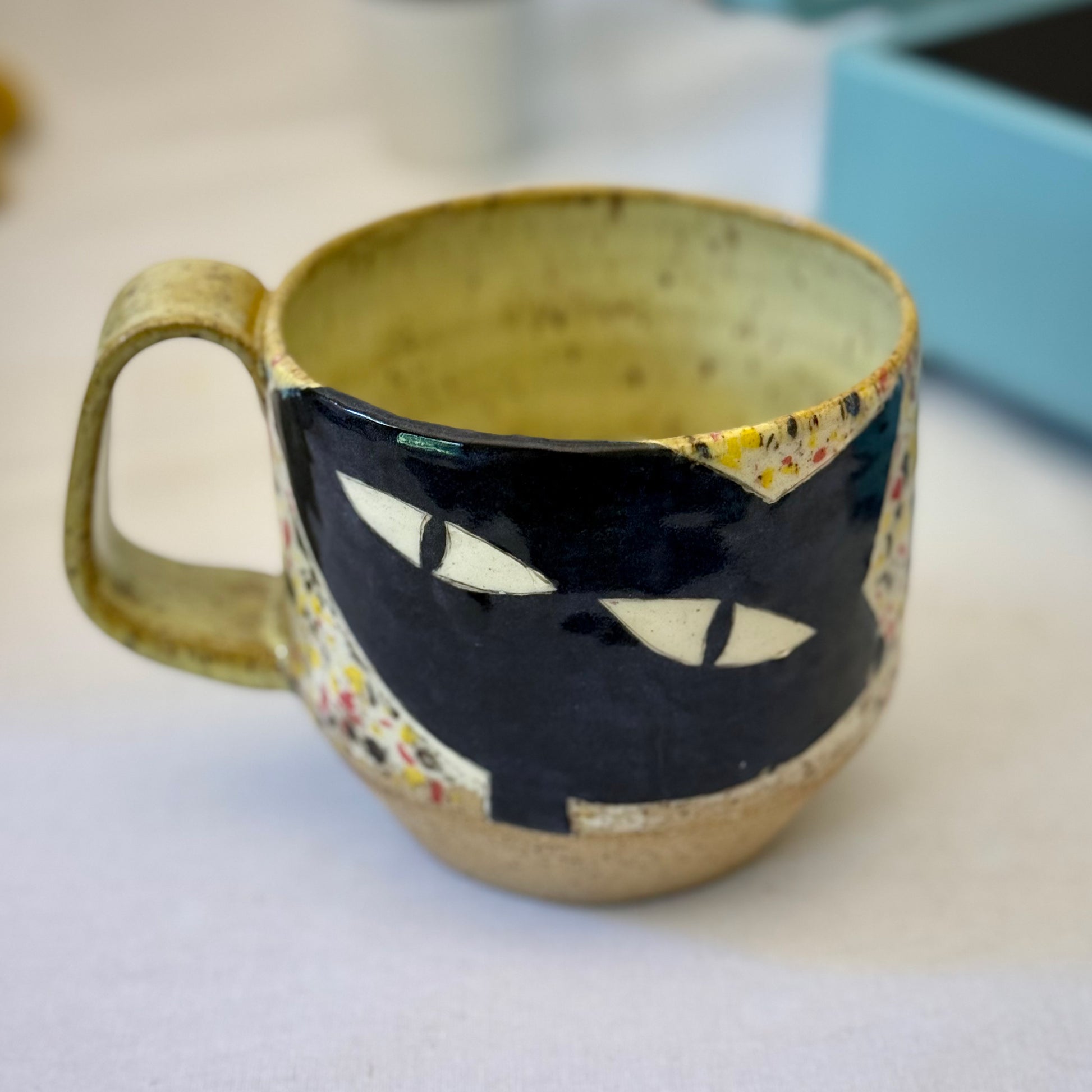 Handmade mug with black cat in red chair and terrazzo pattern