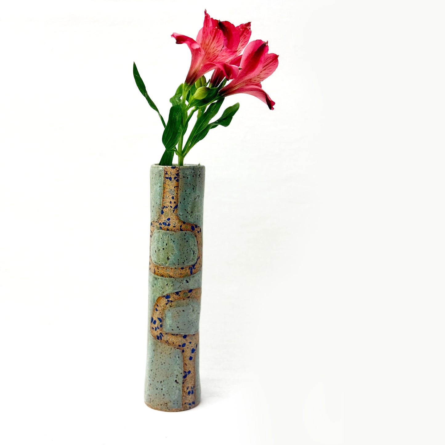 Cylindrical ceramic vase with textured surface holding a pink flower on a white background