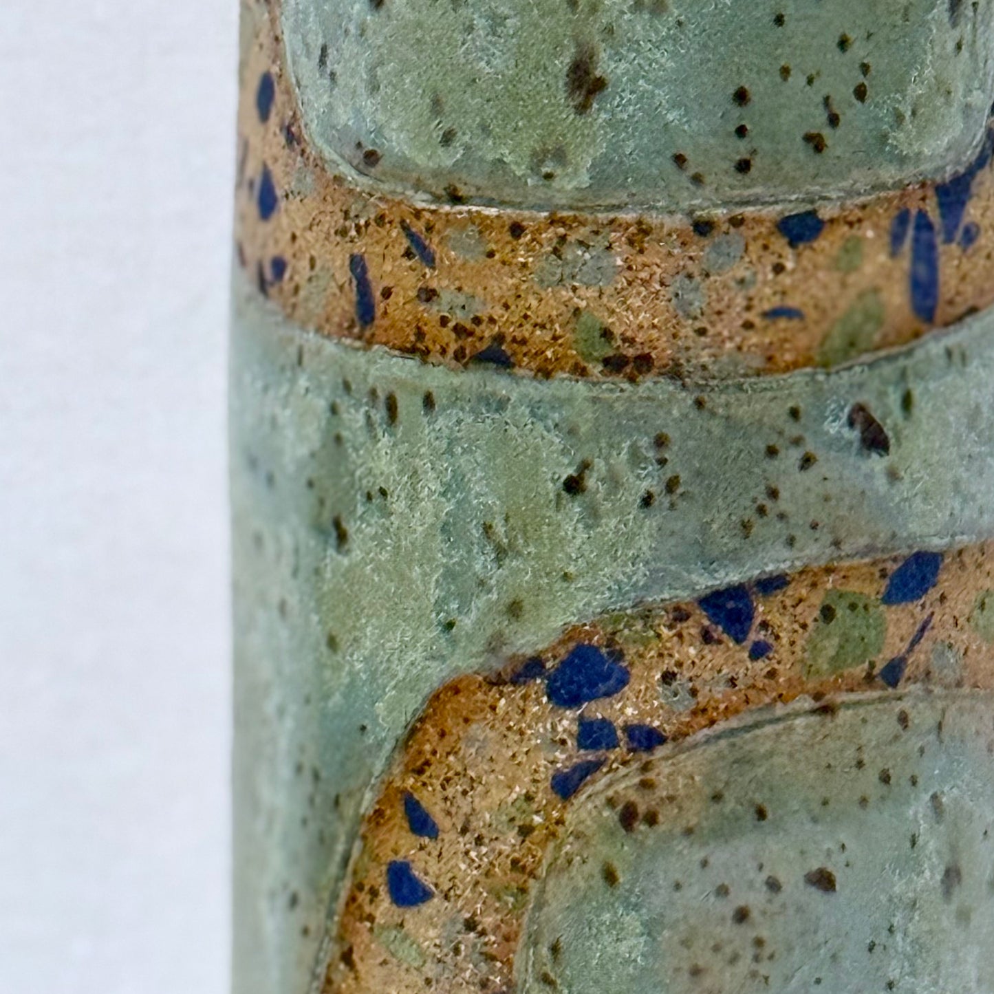 Close-up of a ceramic vase with speckled glaze pattern on a white background