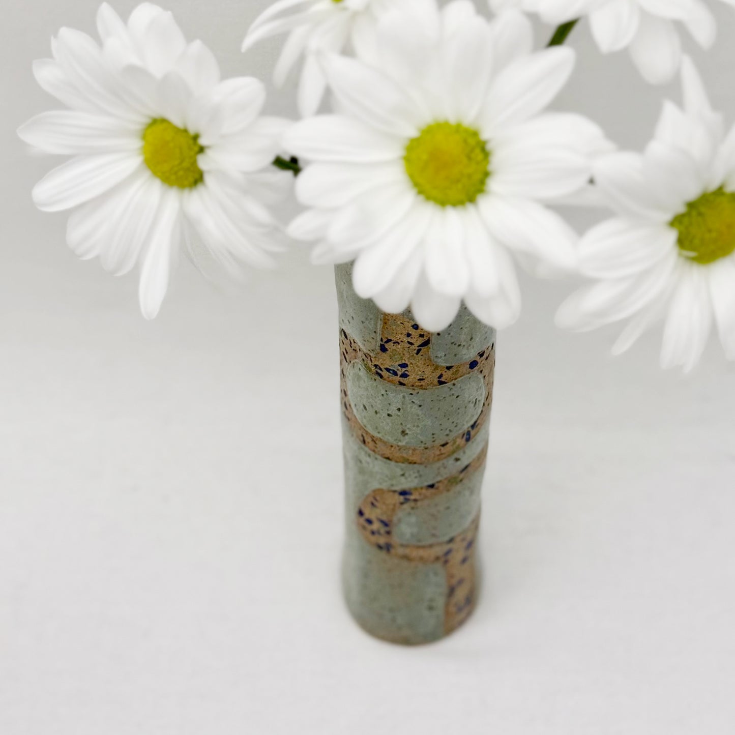 Cylindrical ceramic vase with decorative patterns with white flowers on a light gray background