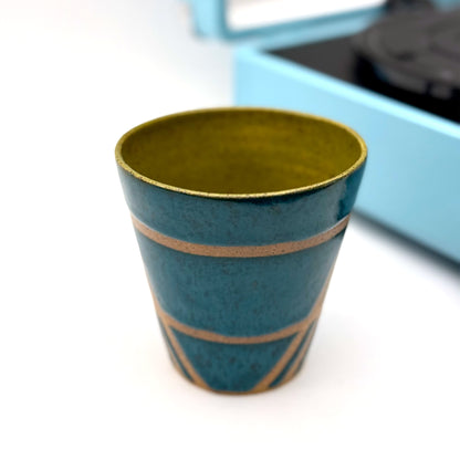 Handmade ceramic mug finished in deep teal and olive glazes with a mid-century–inspired intersecting pattern.