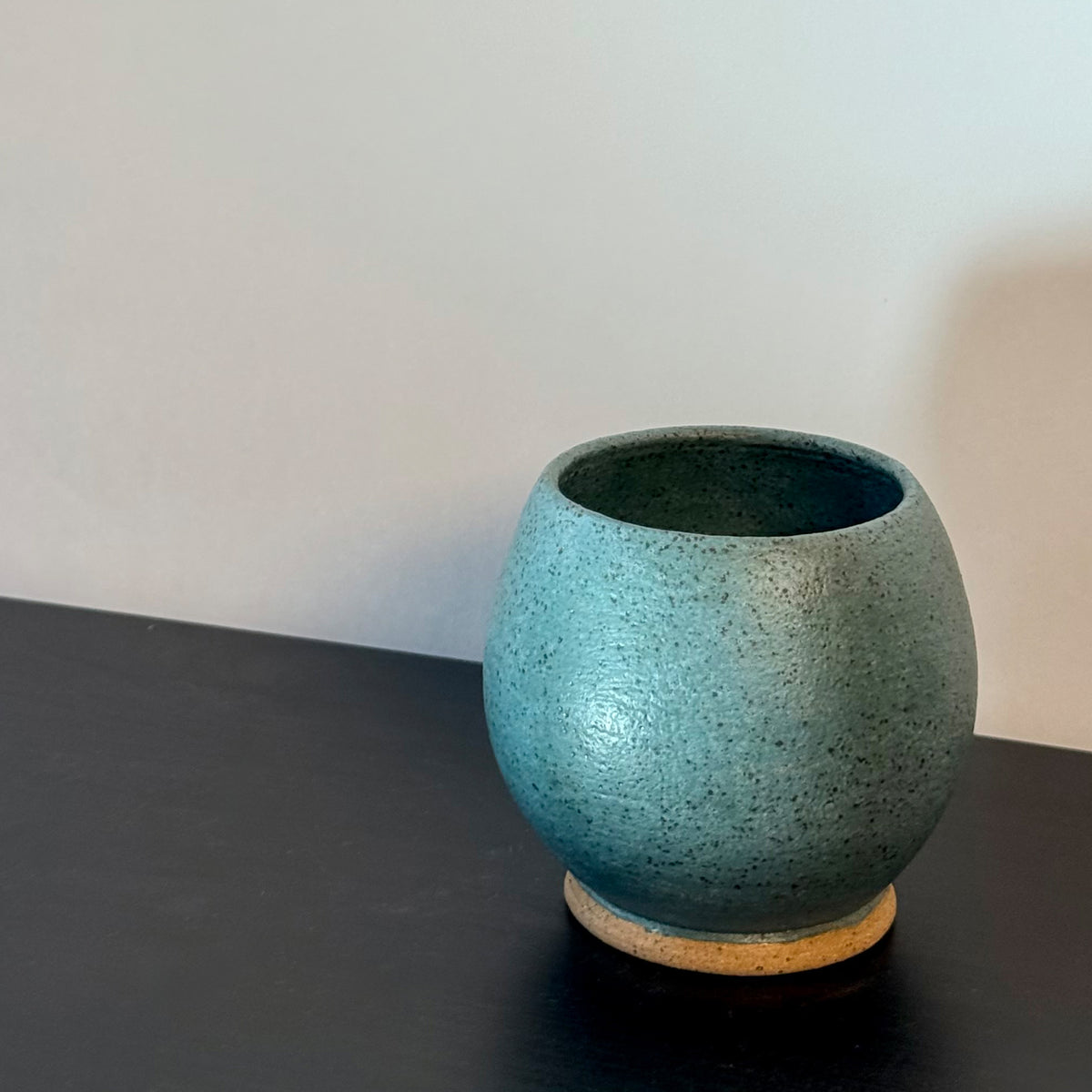 Handmade rounded ceramic vase with a saturated teal glaze, compact orb-shaped body, narrow opening, and exposed natural stoneware foot.
