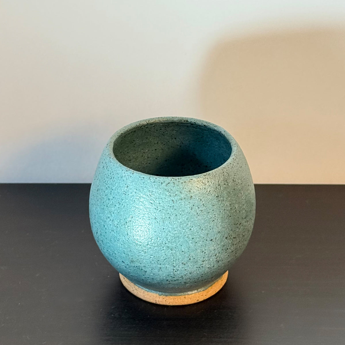 Handmade rounded ceramic vase with a saturated teal glaze, compact orb-shaped body, narrow opening, and exposed natural stoneware foot.
